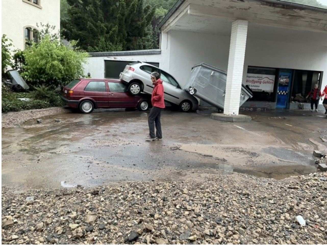 Frau steht vor zerstörten Autos nach Hochwasser